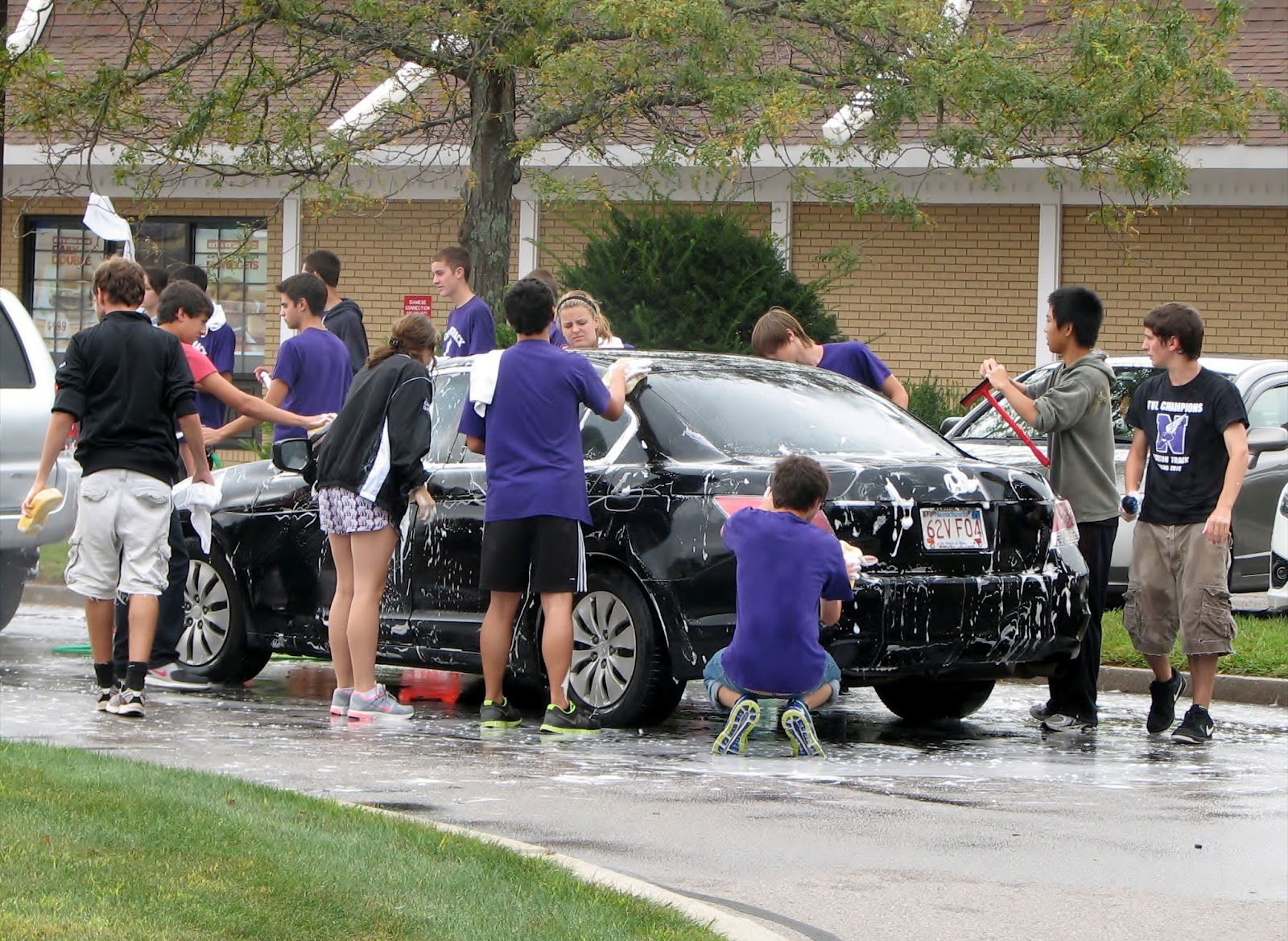 Group of kids washing a black sedan car