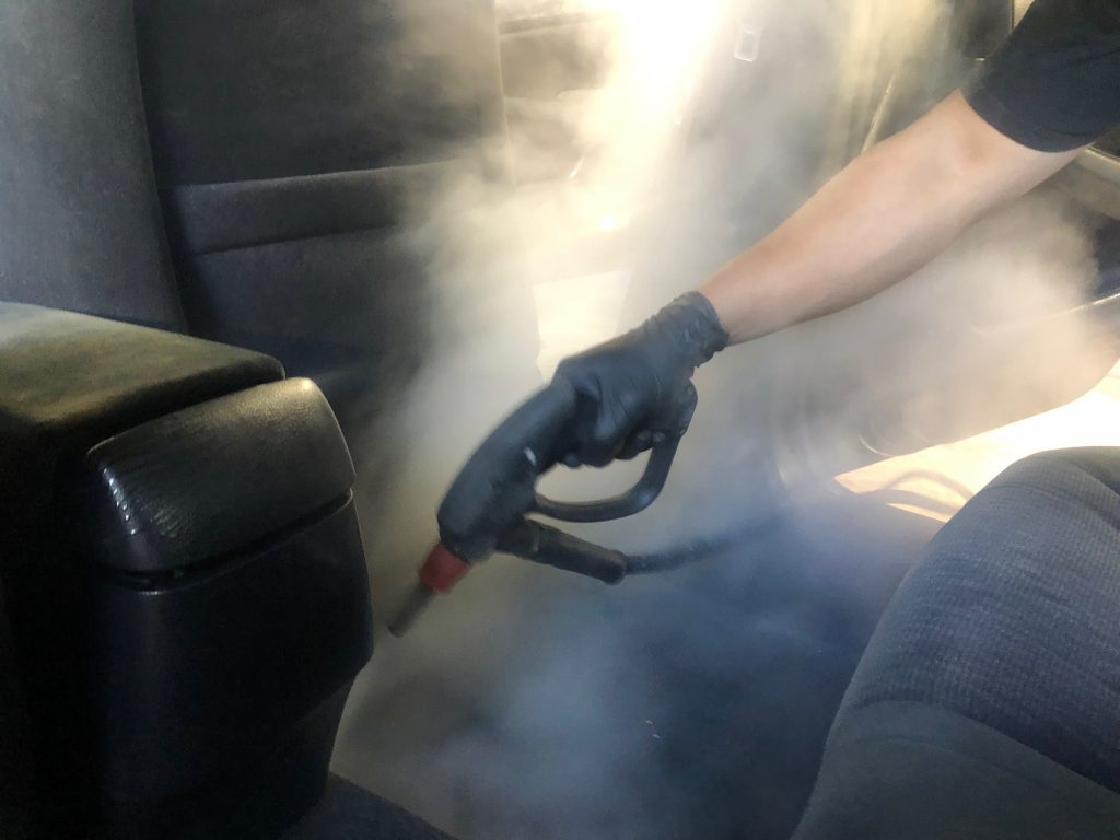 How to make your car smell good - professional car detailer using steam to clean the upholstry